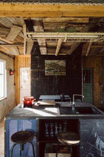 a kitchen with a stove and a sink and two stools at Projektraum Obst und Sterne in Rensow