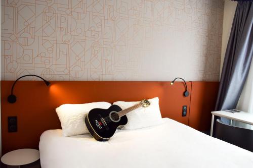 a guitar sitting on top of a bed at ibis Rodez Centre in Rodez
