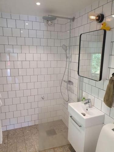 a white tiled bathroom with a sink and a mirror at Stugan in Stockholm