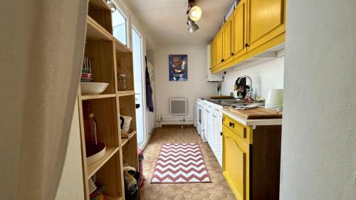 une cuisine avec des armoires jaunes et un tapis rouge et blanc dans l'établissement La Filousine, au Crotoy