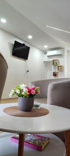 a white table with a vase of flowers on it at Maslina Rooms in Smederevo