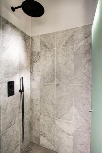 a bathroom with a shower with marble tiles at Canal House with Garden in Amsterdam
