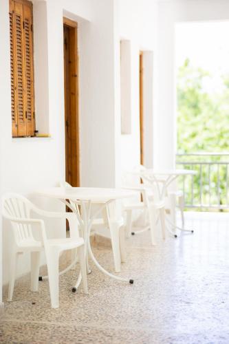 a group of white tables and chairs in a room at Armonia Apartments in Kala Nera