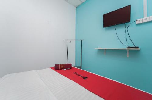 a room with a bed with a flat screen tv at RedDoorz near Universitas YARSI in Jakarta