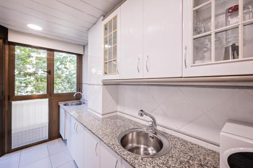 uma cozinha com armários brancos e um lavatório em Aparthotel Napols - Abapart em Barcelona