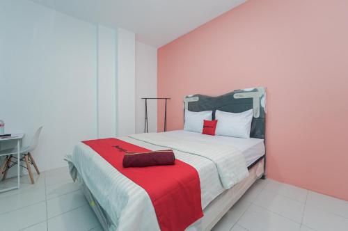 a bedroom with a bed with a red blanket at RedDoorz near Universitas YARSI in Jakarta