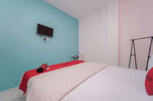 a bedroom with a white bed with a red blanket at RedDoorz near Universitas YARSI in Jakarta