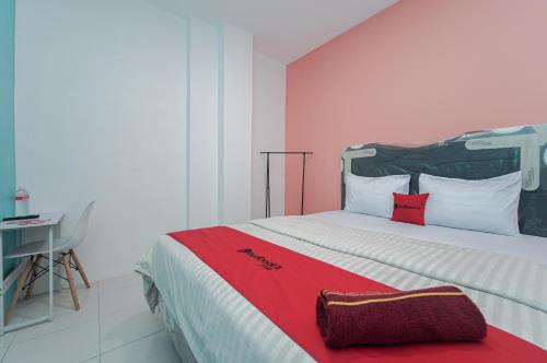 um quarto com uma cama grande e um cobertor vermelho em RedDoorz Syariah at MN One Cempaka Putih em Jakarta
