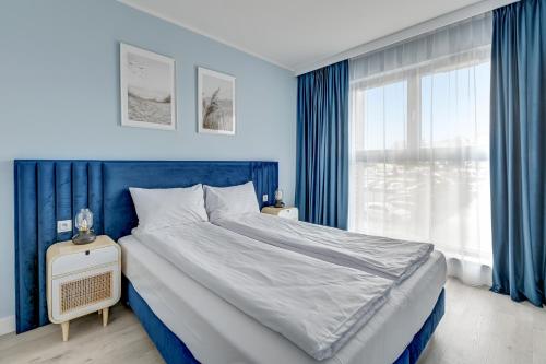 a blue bedroom with a large bed and a window at GRANO APARTMENTS Gdańsk Old Town SPA & Wellness - GRANO APARTMENTS Gdańsk Residence SPA & Wellness in Gdańsk