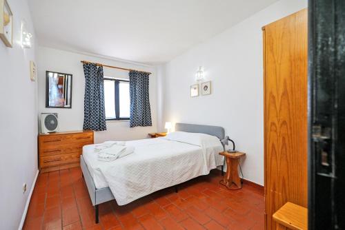 Schlafzimmer mit einem Bett, einer Kommode und einem Fenster in der Unterkunft A51 - Torraltinha Sunset Apartment in Lagos