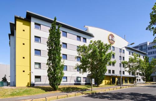 un hotel con un edificio blanco y amarillo en B&B HOTEL Frankfurt-Niederrad en Frankfurt