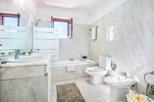 a white bathroom with a toilet and a sink at Villa Mar Gale in Galé