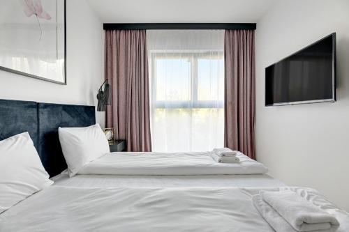 a bedroom with a bed and a window with a television at GRANO APARTMENTS Gdańsk Old Town SPA & Wellness - GRANO APARTMENTS Gdańsk Residence SPA & Wellness in Gdańsk
