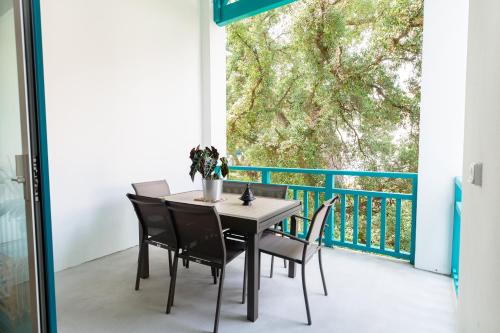 une table et des chaises sur un balcon avec une grande fenêtre dans l'établissement Atlantic Selection - Ene Etchola - Proche du port de Capbreton, à Capbreton