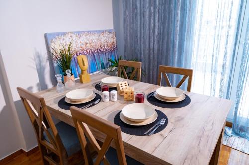 einen Esstisch mit Stühlen und einen Holztisch mit Tellern in der Unterkunft Eunoia Luxury Apartment Thessaloniki in Thessaloniki