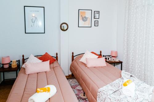 2 Betten in einem Schlafzimmer mit rosa Bettwäsche und Kissen in der Unterkunft Eunoia Luxury Apartment Thessaloniki in Thessaloniki