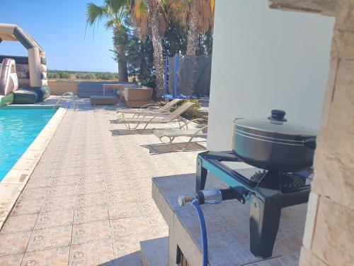 a grill sitting on a table next to a swimming pool at Larnaca Mansion Ideal for 3 Families or more in Larnaka