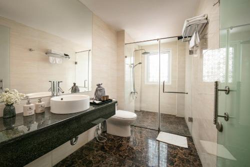 W łazience znajduje się umywalka, toaleta i prysznic. w obiekcie Hanoi La Palm Premier Hotel & Spa w mieście Hanoi
