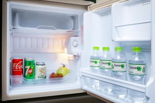 an open refrigerator with bottles of soda and water at Hanoi La Palm Premier Hotel & Spa in Hanoi