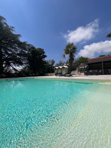 a swimming pool with blue water in front of a house at Domaine d'En Fargou in Saint-Sulpice