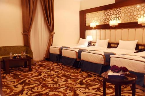 a hotel room with three beds and a couch at فندق الاندلس الماسي - Alandalus Diamond Hotel in Al Madinah