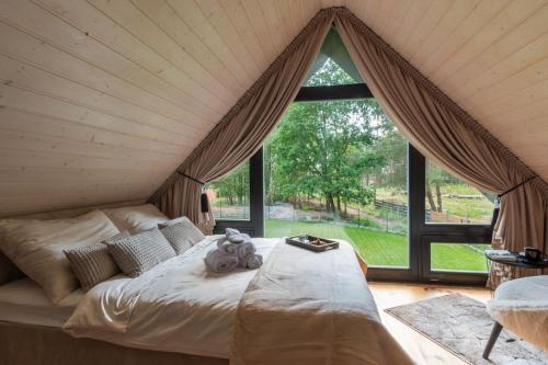 a bed in a room with a large window at Po prostu Piękna! Domek nad jeziorem in Stare Jabłonki