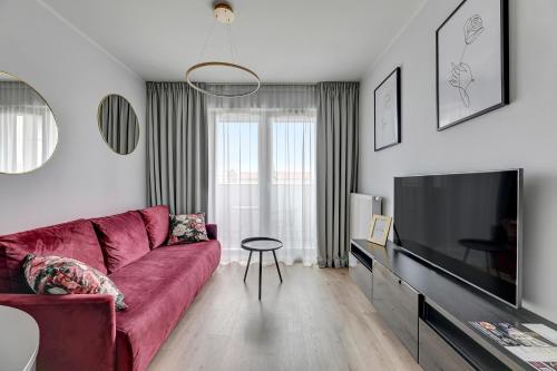 a living room with a red couch and a flat screen tv at GRANO APARTMENTS Gdańsk Old Town SPA & Wellness - GRANO APARTMENTS Gdańsk Residence SPA & Wellness in Gdańsk