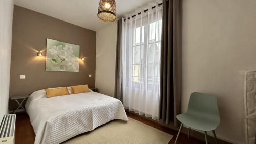 une chambre avec un lit et une fenêtre avec une chaise dans l'établissement Jaliane, maison de pêcheur, à Saint-Valery-sur-Somme