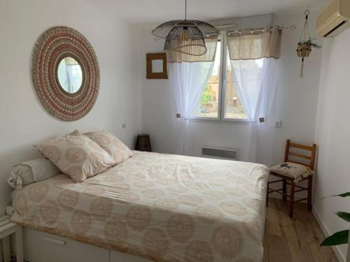 Schlafzimmer mit einem Bett, einem Spiegel und einem Fenster in der Unterkunft Appartement au bord de l'Hérault in Agde