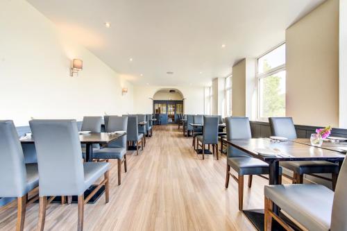 a dining room with tables and blue chairs at Onich Hotel & Lochside Beach Pods in Onich