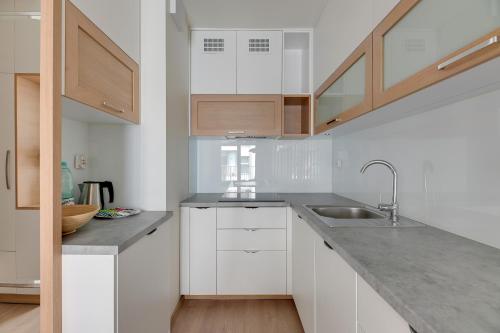 a kitchen with white cabinets and a sink at GRANO APARTMENTS Gdańsk Old Town SPA & Wellness - GRANO APARTMENTS Gdańsk Residence SPA & Wellness in Gdańsk
