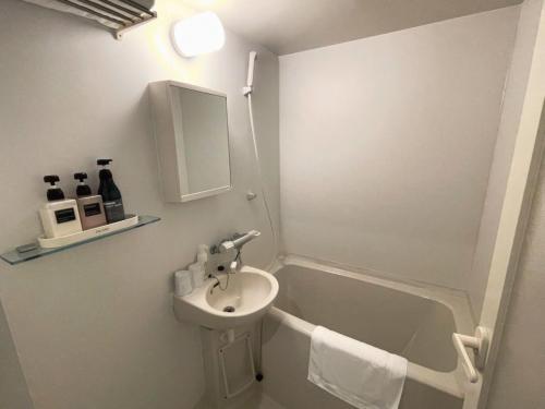y baño blanco con lavabo y bañera. en Shinjuku Sun Park Hotel, en Tokio