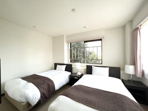 een slaapkamer met 2 bedden en een raam bij Shinjuku Sun Park Hotel in Tokyo