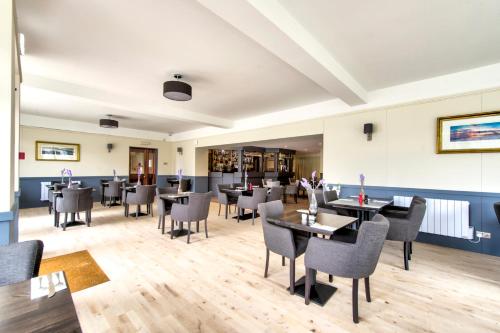 a restaurant with tables and chairs in a room at Onich Hotel & Lochside Beach Pods in Onich