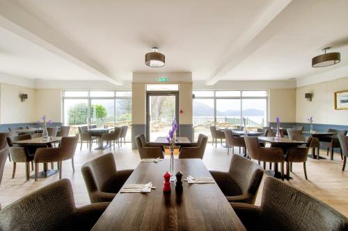 uma sala de jantar com mesas, cadeiras e janelas em Onich Hotel & Lochside Beach Pods em Onich