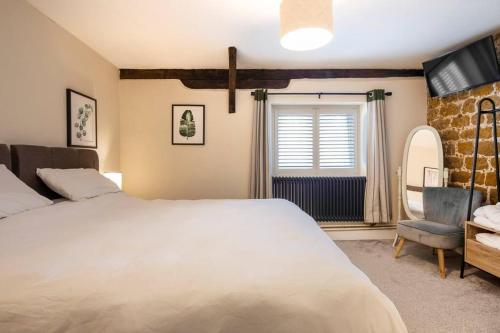 ein Schlafzimmer mit einem großen weißen Bett und einem Stuhl in der Unterkunft The Cart Lodge - relaxing rural spa break in Pentney