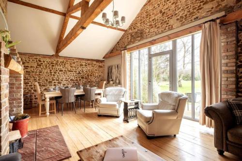 a living room with a brick wall and a table and chairs at The Cart Lodge - relaxing rural spa break in Pentney