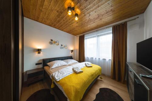 1 dormitorio con cama amarilla y TV en Apartmán B4 Hrabušice, en Hrabušice