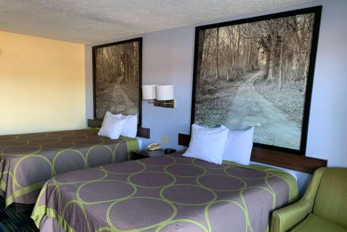 a hotel room with two beds and a chair at Super 8 by Wyndham Jackson in Jackson