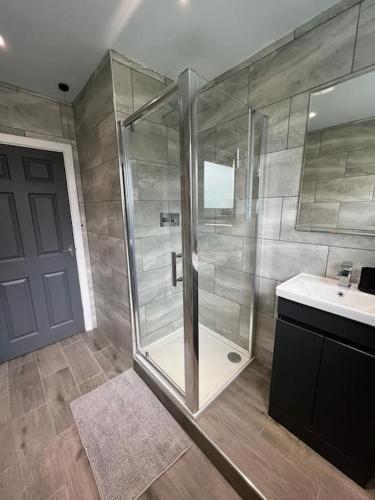 a bathroom with a glass shower and a sink at Superb Three Bed Garnant Duplex! in Garnant