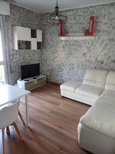 ein Wohnzimmer mit einem weißen Sofa und einem Tisch in der Unterkunft 4 PASSI DAL CENTRO in Brescia