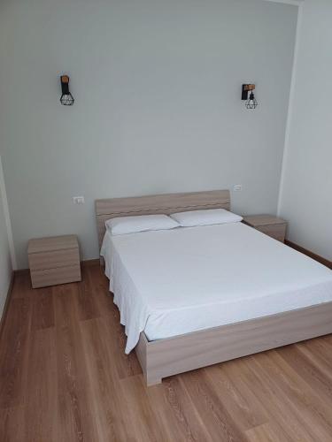 una camera da letto con letto, lenzuola bianche e pavimenti in legno di 4 PASSI DAL CENTRO a Brescia