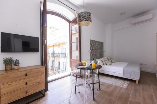 a living room with a table and a bed and a tv at Apartamento-Loft Especería Black in Málaga