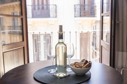 a bottle of wine and a bowl of bread on a table at Apartamento-Loft Especería Black in Málaga