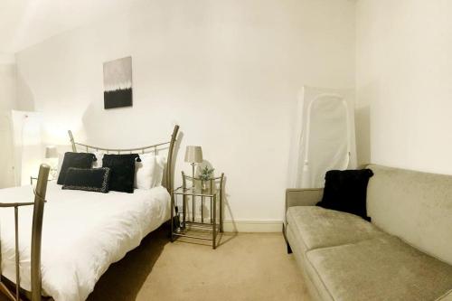 a white bedroom with a bed and a couch at Beautiful Central Open plan living! in Manchester