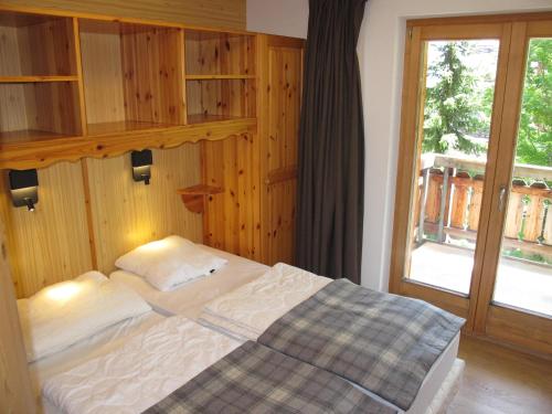 uma cama num quarto com uma grande janela em Wohnung CHOTTES NEND230 em Nendaz