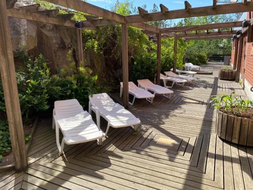 a wooden deck with white chairs and a pergola at ProfilHotels Nacka in Stockholm