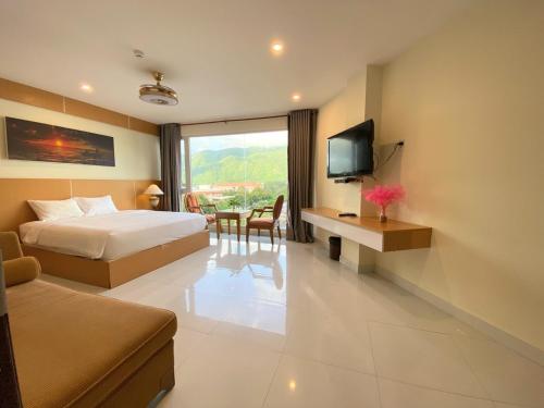 um quarto de hotel com uma cama, uma secretária e uma televisão em Conson Hotel em Con Dao