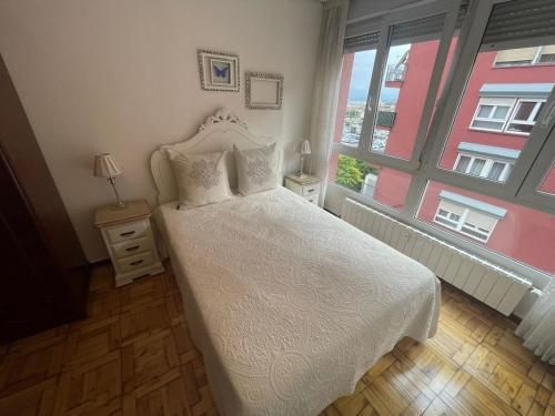 1 dormitorio con cama blanca y ventana en Piso cerca de las estaciones, en Santander