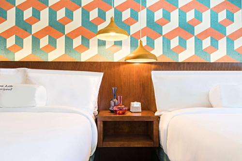 a room with two beds and a table between two beds at Unscripted Durham, Part of JDV by Hyatt in Durham